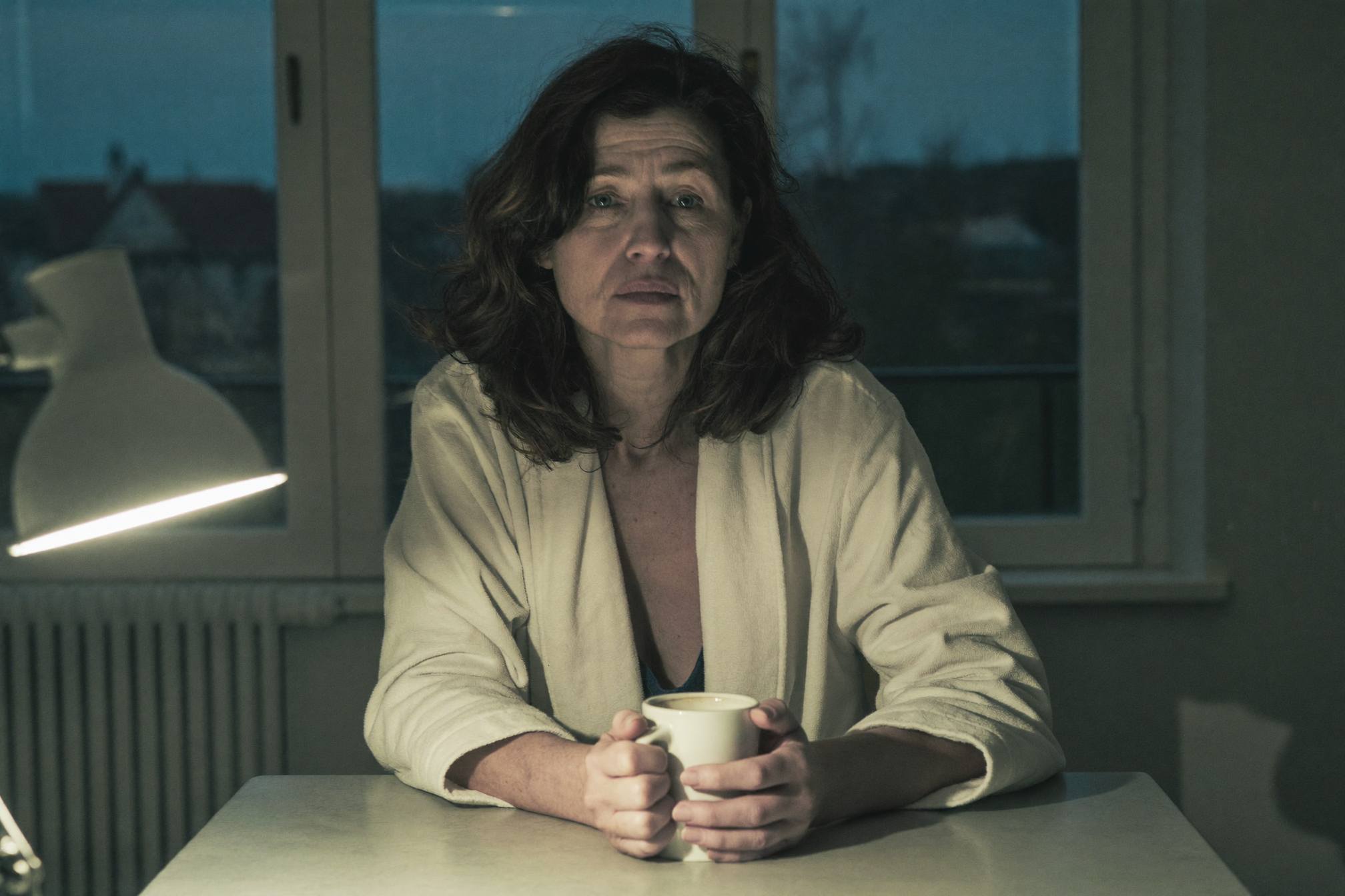 Frau früh morgens am Küchentisch